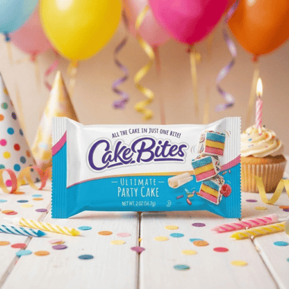 Festliche 56,7g Packung „CakeBites Ultimate Party Cake“ vor buntem Hintergrund mit Luftballons. Gezeigt werden bunte Kuchenschichten mit weißem Guss und Streuseln.